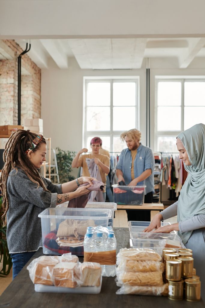 A diverse group of volunteers sorting clothes and food items at an indoor donation center.