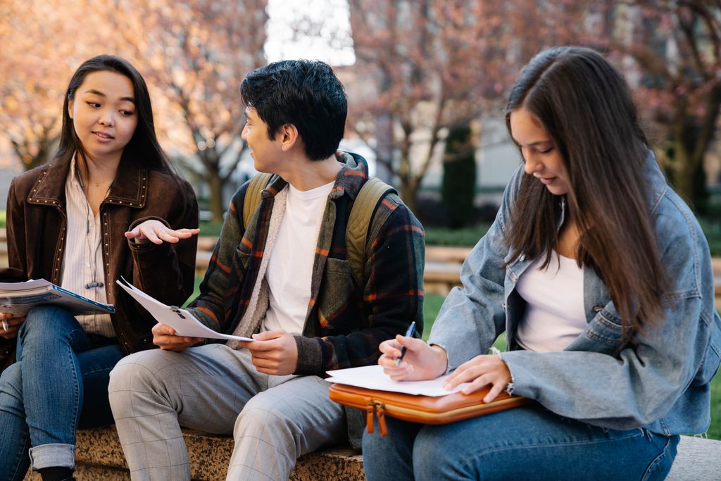 Three students sitting and studying together in a campus setting.