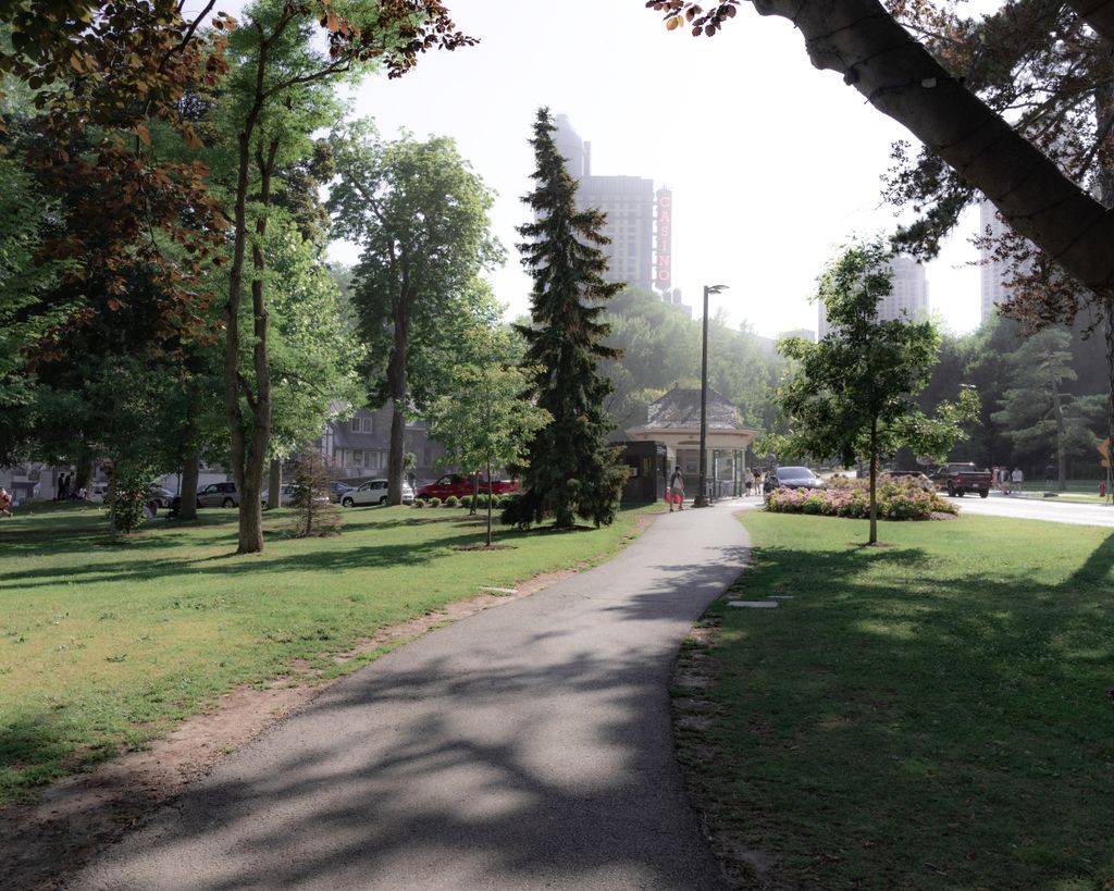 Tranquil park walkway in Niagara Falls, ON, surrounded by trees and urban scenery.